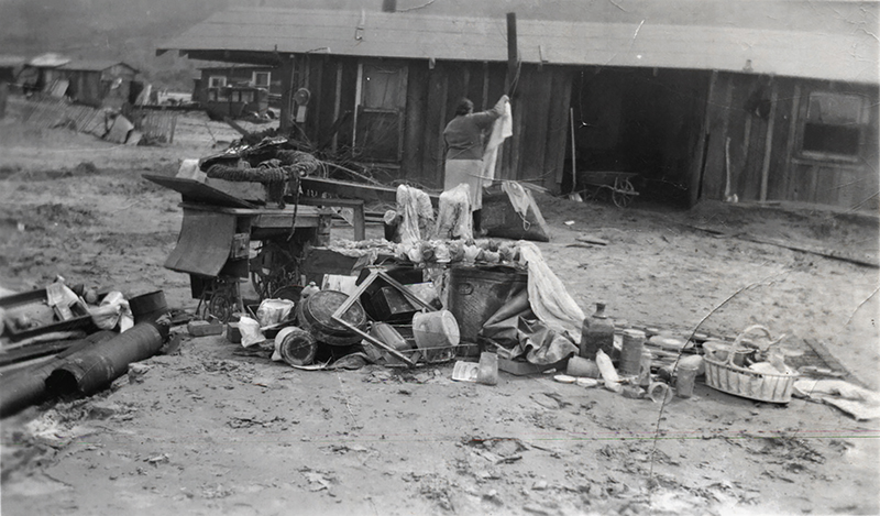 Unidentified woman sifts through her possessions in front of her wrecked home.